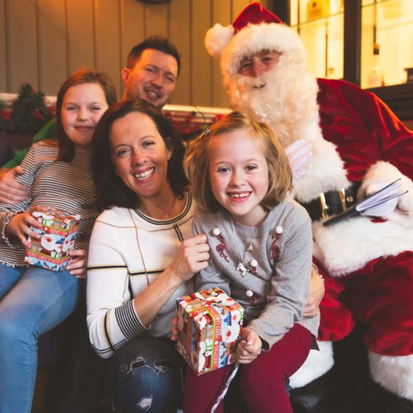 A family holding gifts smiling with Santa