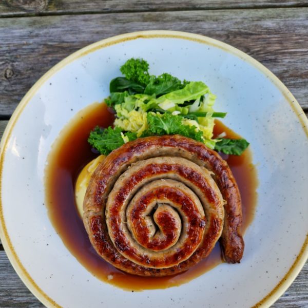 Cumberland Sausage Whirl on a bed of mash potato with seasonal green veg, drenched in gravy
