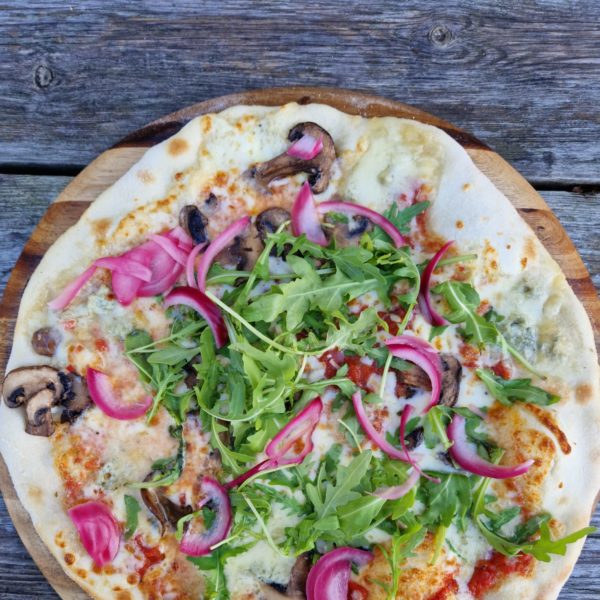 Red onion, mushrooms, and rocket on a pizza.